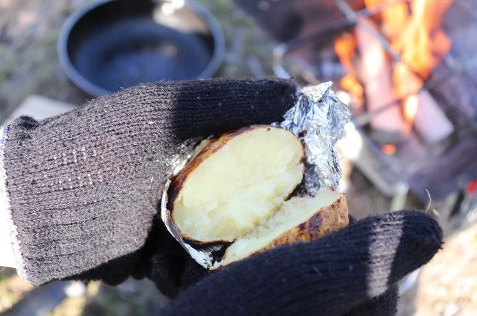 ホイル焼きにしたじゃがいもを手で割っている。