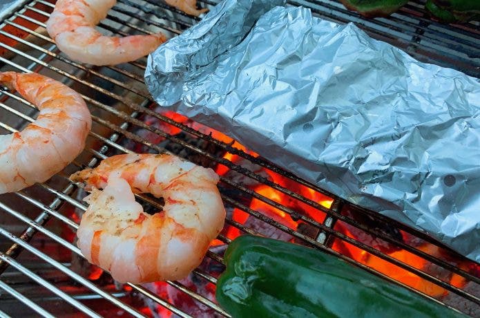 バーベキュー網の上の具材とホイル包み焼き