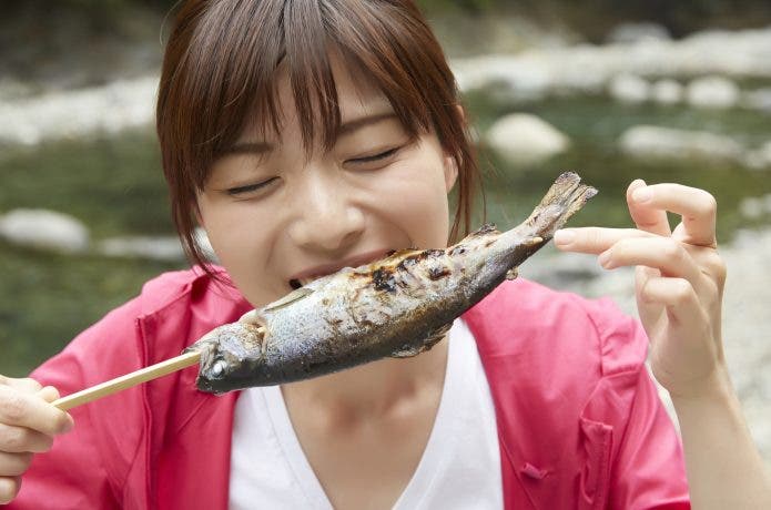 川で魚を食べる女性