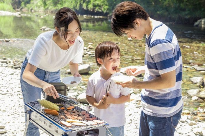 川沿いでバーベキューをする親子