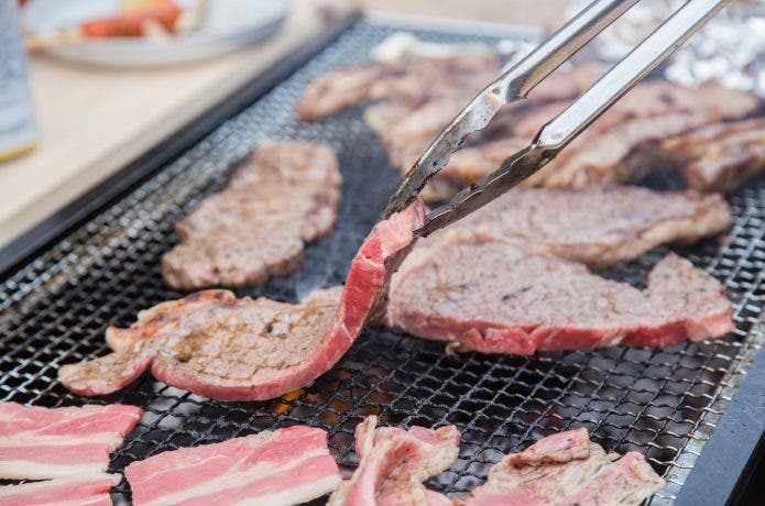バーベキューコンロで肉を焼いている