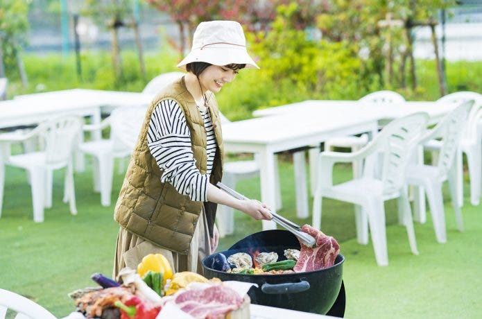 女性がバーベキューで大きな肉を焼く