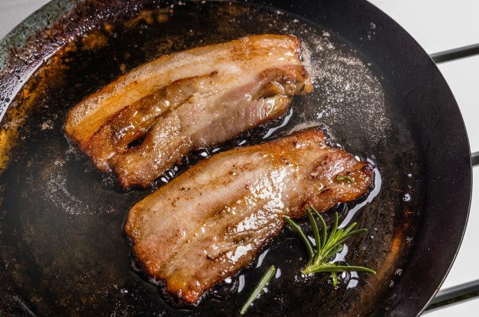 スキレットで焼かれ脂が滲むベーコン